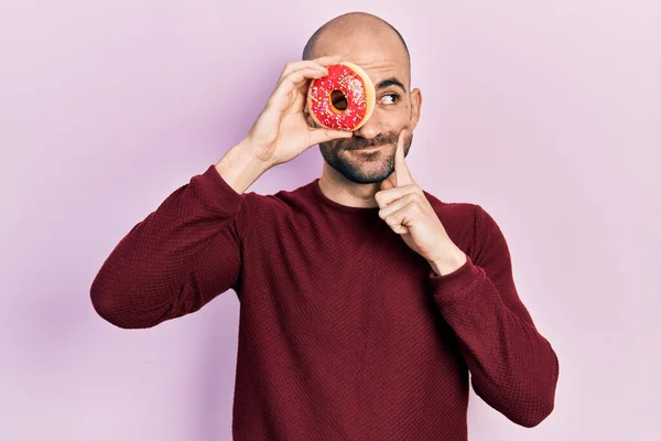 Young Bald Man Holding Tasty Colorful Doughnut Eye Serious Face — Stock Photo, Image