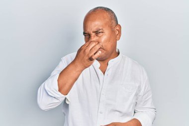 Orta yaşlı, gündelik kıyafetler giyen, pis ve iğrenç bir koku alan, nefesini burnunda tutan Latin bir adam. Kötü kokuyor. 