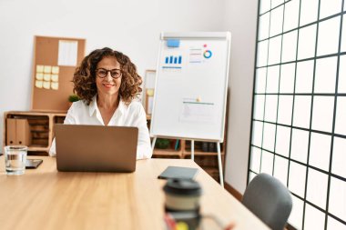 Ofiste çalışırken gülümseyen orta yaşlı İspanyol kadın.