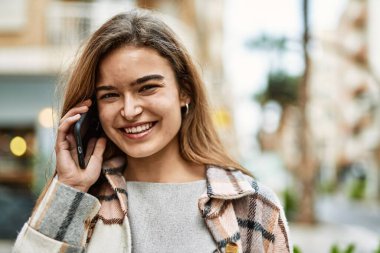 Sokakta akıllı telefondan konuşan genç sarışın kadın.