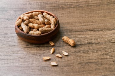 Tahta bir masada kasedeki fıstık demeti.