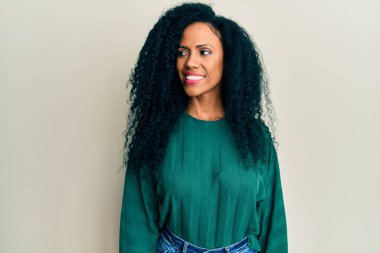 Orta yaşlı Afro-Amerikalı kadın günlük giysiler giyiyor, rahat profil pozu veriyor doğal bir yüzü ve kendine güvenen bir gülüşü var.. 
