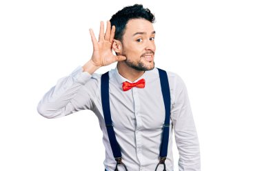 Sakallı, hippi görünümlü, papyonlu, pantolon askısı takmış, ağzı kulaklarında dedikoduları ve dedikoduları dinleyen İspanyol bir adam. Sağırlık kavramı. 