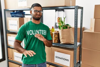Genç Hintli gönüllü, bağış kutusunu tutan iğrenç bir yüz ifadesi var. Tiksinti tepkisi yüzünden tiksinmiş ve korkmuş bir ifade takınıyor. Eller havada. 
