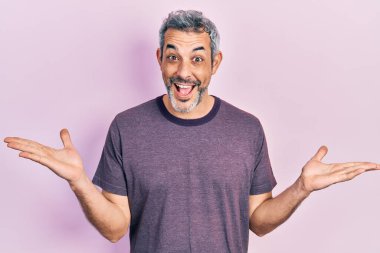 Handsome middle age man with grey hair wearing casual t shirt celebrating victory with happy smile and winner expression with raised hands 