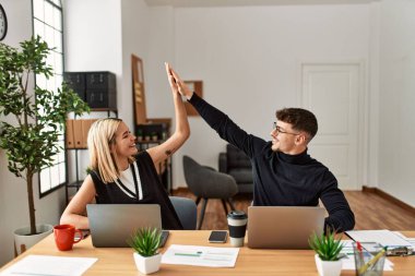 Mutluluktan gülümseyen ve ofiste beşlik çakan iki iş adamı.