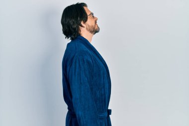 Bornoz ve gözlük takan orta yaşlı beyaz bir adam, rahat profil pozu, kendine güvenen bir gülümsemeyle doğal bir poz.. 