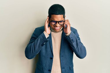 Zarif kıyafetler giyen yakışıklı İspanyol adam ve yüksek sesli müzik sesi için kulaklarını parmaklarıyla kapatan gözlüklü adam. sağır kavramı. 