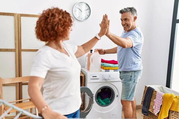 中年男女夫妇高五高举双手 在洗衣店里挂着衣服 — 图库照片