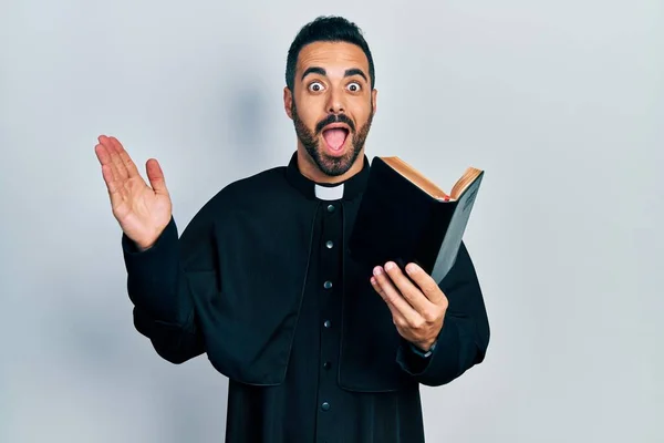 Pohledný Hispánský Kněz Vousy Drží Bibli Křesťanský Kříž Slaví Blázen — Stock fotografie
