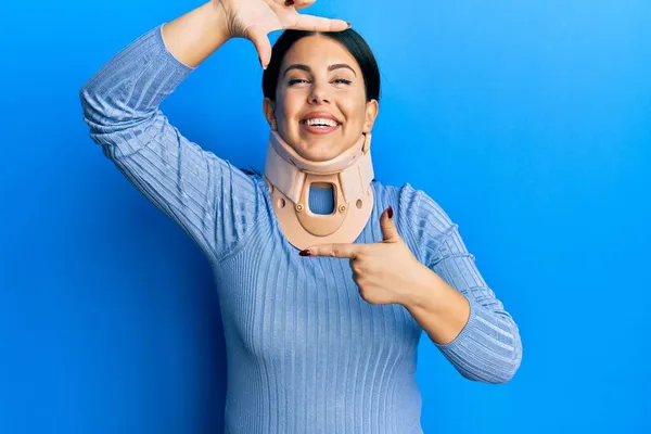 子宮頸部の襟を身に着けている美しいブルネットの女性は幸せな顔で手と指でフレームを作る笑顔 創造性と写真の概念 — ストック写真