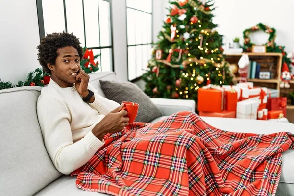 Joven Hombre Afroamericano Sentado Sofá Bebiendo Café Por Árbol Navidad — Foto de Stock