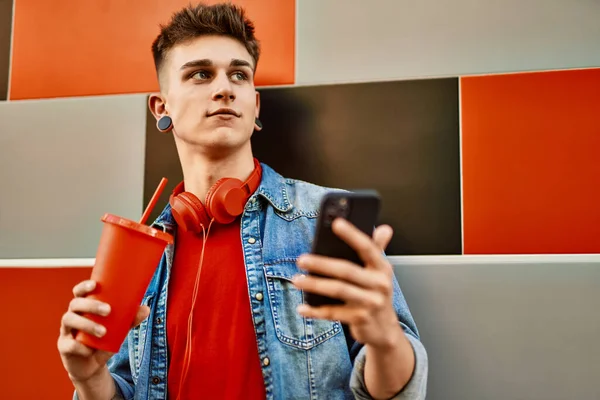 Jovem Caucasiano Cara Bebendo Refrigerante Usando Smartphone Encostado Parede — Fotografia de Stock