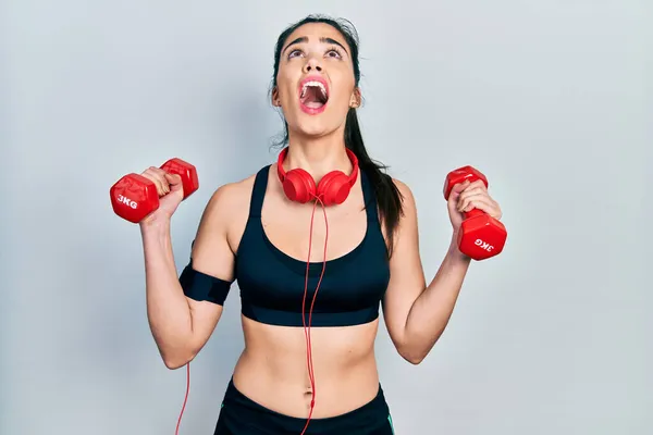 Joven Chica Hispana Usando Ropa Deportiva Usando Mancuernas Enojadas Locas —  Fotos de Stock