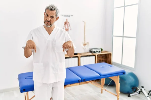 Middle Age Hispanic Therapist Man Working Pain Recovery Clinic Pointing — Stockfoto