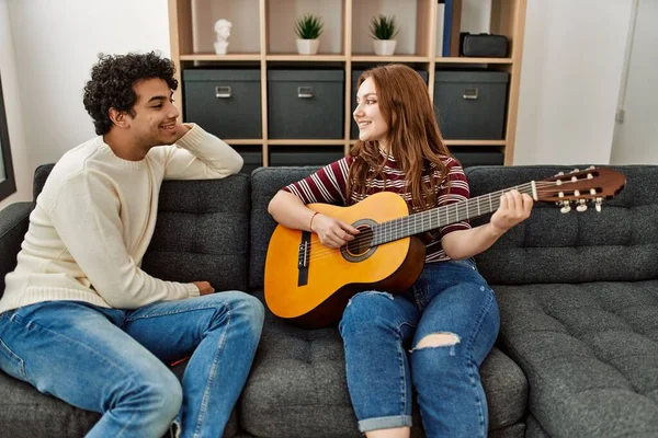 Jovem Casal Sorrindo Feliz Tocando Guitarra Clássica Sentado Sofá Casa — Fotografia de Stock