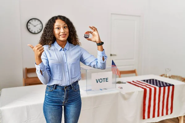 後ろ手と親指を上げ自信を持って笑顔で投票することによって政治運動に立っている美しいヒスパニック系の女性 — ストック写真