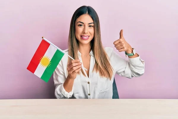 Jovem Hispânica Segurando Bandeira Curdistão Sentado Mesa Sorrindo Feliz Positivo — Fotografia de Stock