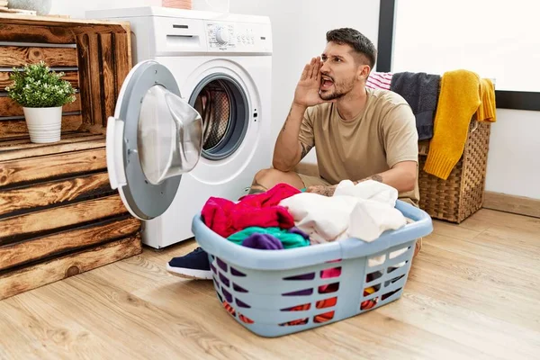 若いハンサムな男は洗濯機の叫びに汚れた洗濯機を入れ 口の上に手で横に大声で叫んでいます コミュニケーションの概念 — ストック写真