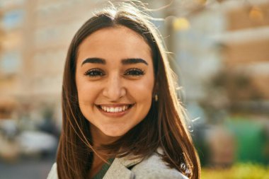 Genç İspanyol kız gülümseyerek şehirde mutlu mesut dikiliyor..