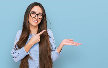 Gündelik kıyafetler giyen ve gözlüklü genç İspanyol kız kameraya hayret ediyor ve gülümsüyor.. 