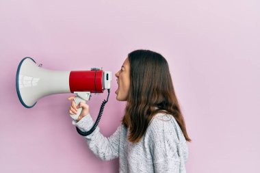 Genç esmer kadın pembe izole arka planda megafonla bağırıyor ve çığlık atıyordu.