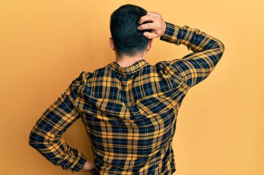 Latin asıllı genç adam gündelik kıyafetleri ters giyip elleri kafasında şüpheyi düşünüyor. 