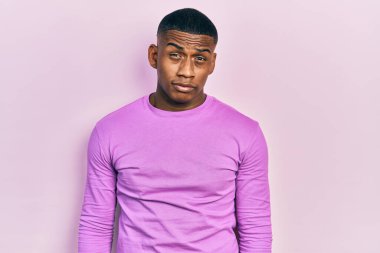 Sıradan pembe kazak giyen, kuşkucu ve gergin genç siyahi bir adam sorun yüzünden surat asıyor. negatif kişi. 