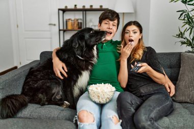 Kafkasyalı genç bir çift kanepede oturmuş, evde köpekleriyle film izliyor..