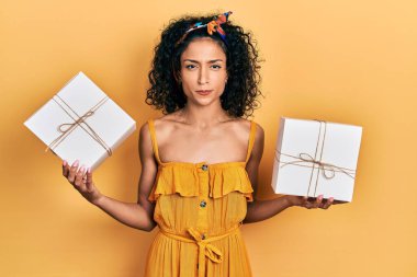 Elinde hediyeler tutan genç Latin kız şüpheci ve gergin, sorun yüzünden surat asıyor. negatif kişi. 