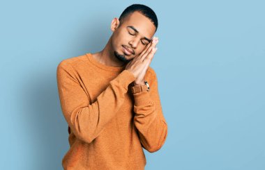 Genç Afro-Amerikan adam günlük kıyafetler giyip uyuyordu. Yorgundu. Hayal kuruyordu ve elleriyle poz veriyordu.. 