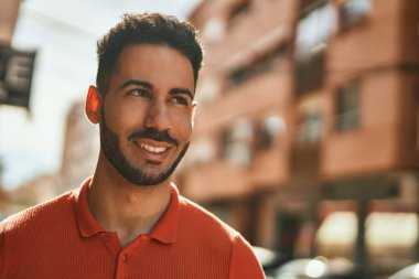 Genç İspanyol adam gülümseyerek şehirde mutlu mesut dikiliyor..
