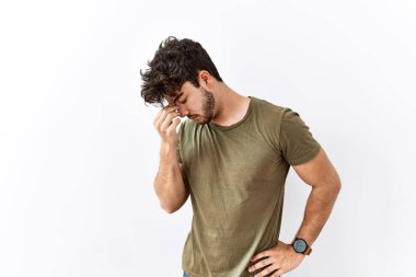 Hispanic man standing over isolated white background tired rubbing nose and eyes feeling fatigue and headache. stress and frustration concept. 