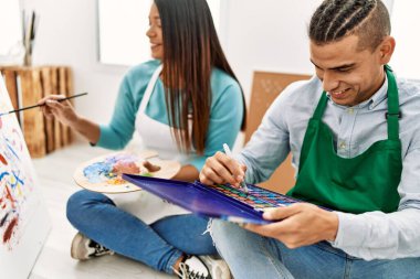 Genç Latin ressam çift mutlu bir şekilde resim stüdyosunun zemininde oturuyor..