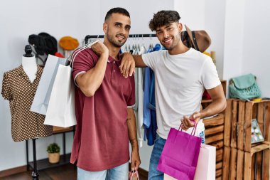 İki İspanyol müşterinin alışveriş torbalarını tutarken mutlu bir gülümsemesi var..