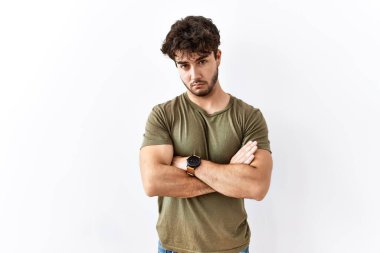 Hispanic man standing over isolated white background skeptic and nervous, disapproving expression on face with crossed arms. negative person. 
