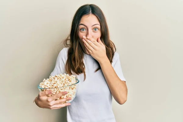 Ung Brunett Kvinna Äter Popcorn Täcker Munnen Med Handen Chockad — Stockfoto