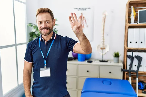 Ağrı Kesici Kliniğinde Çalışan Orta Yaşlı Fizyoterapist Dört Numarayı Gösterip — Stok fotoğraf