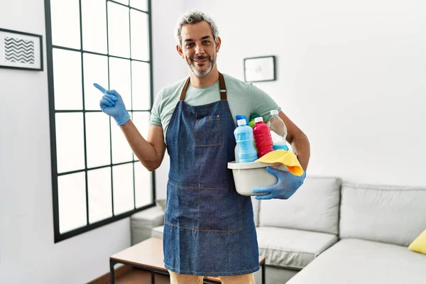 Middle Age Hispanic Man Wearing Cleaner Apron Holding Cleaning Products — Zdjęcie stockowe