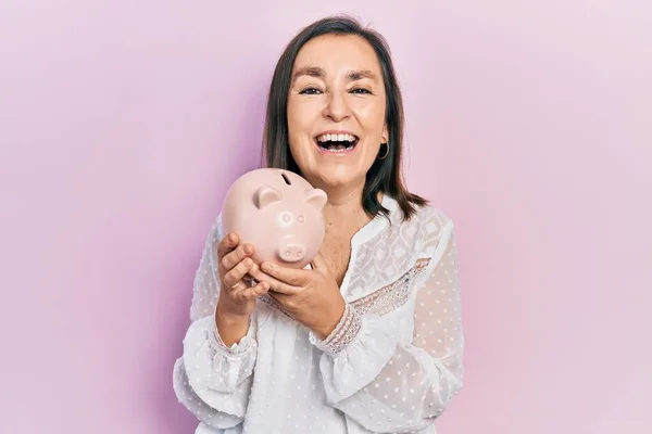 Mulher Hispânica Meia Idade Segurando Porquinho Banco Sorrindo Rindo Duro — Fotografia de Stock