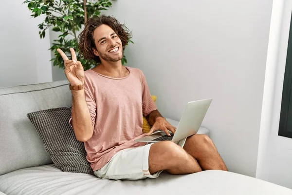 Joven Hispano Sentado Sofá Casa Usando Portátil Sonriente Mirando Cámara —  Fotos de Stock