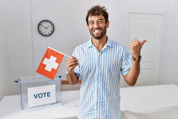 Jovem Homem Bonito Eleição Campanha Política Segurando Bandeira Suíça Apontando — Fotografia de Stock