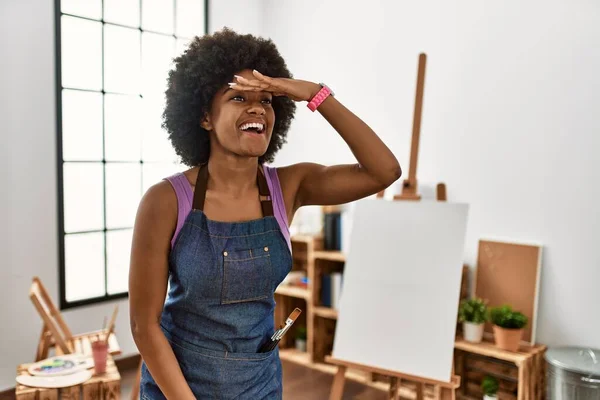 アートスタジオでアフロヘアの若いアフリカ系アメリカ人女性は 頭の上を手で遠くを見て非常に幸せと笑顔 検索の概念 — ストック写真