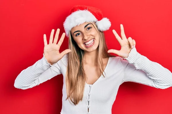 美しいですヒスパニック女性身に着けていますクリスマス帽子ショーとポイントアップとともに指番号8ながら笑顔自信と幸せ — ストック写真