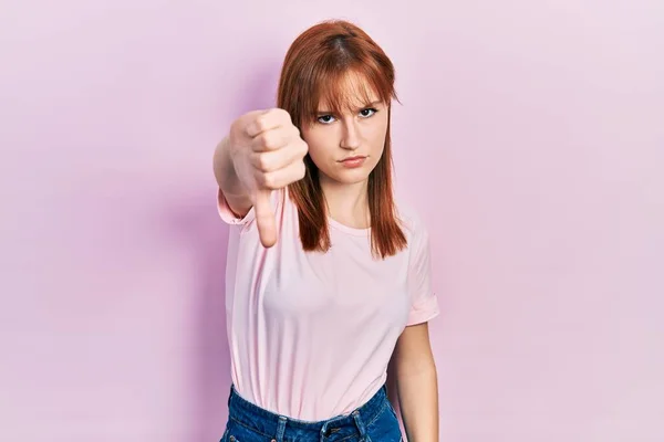 红头发的年轻女人穿着宽松的粉色T恤 看起来很不高兴 很生气 表现出拒绝和负面的手势 不好的表达方式 — 图库照片
