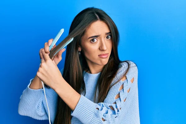 Young Hispanic Girl Holding Hair Straightener Clueless Confused Expression Doubt — Stock Photo, Image