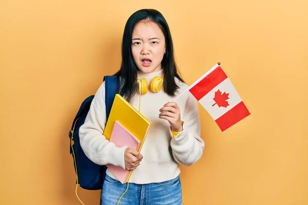年轻的中国女孩面带微笑地交换着加拿大国旗 脸上带着怀疑和讽刺的表情 张大了嘴 吃惊极了 — 图库照片