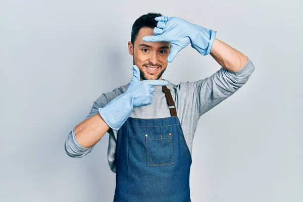 Young Hispanic Man Wearing Apron Gloves Smiling Making Frame Hands — Stockfoto
