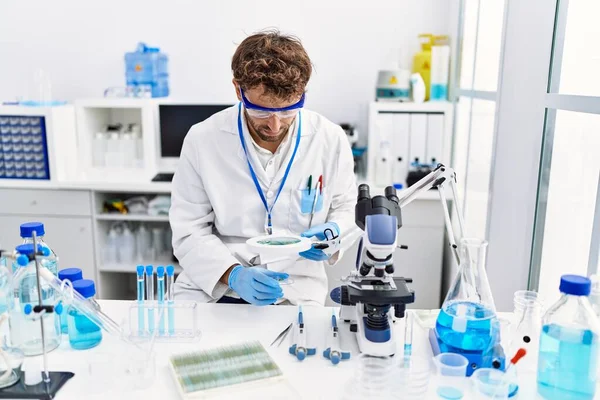Young Hispanic Man Wearing Scientist Uniform Using Loupe Laboratory — Stock Photo, Image