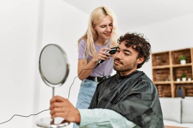 Genç bir kadın evdeki erkek arkadaşına saç kesiyor..